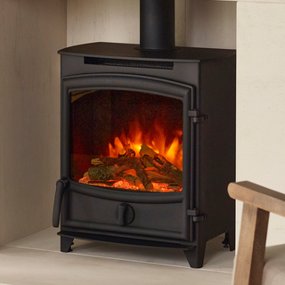Black freestanding stove with glowing logs inside, placed against a neutral wall.