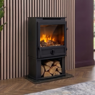 Black freestanding stove with fire burning inside, next to a stack of wood against a striped wall.