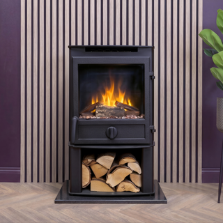 Black freestanding stove with fire burning inside, surrounded by stacked wood logs against a striped wall.